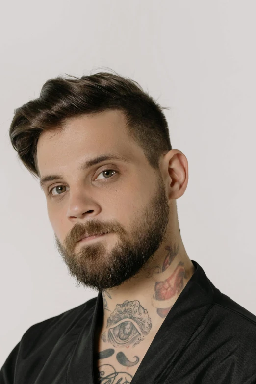 a man with a beard wearing a black robe, a tattoo, inspired by Adam Szentpétery, headshot profile picture, non binary model, great _ hairstyle, uploaded