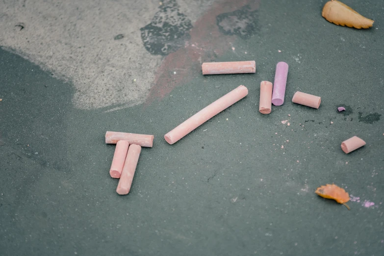 a group of pink chalk sticks laying on the ground, by Elsa Bleda, pexels contest winner, graffiti, slate, muted colors. ue 5, childhood, gray concrete