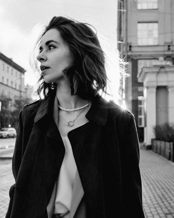 a black and white photo of a woman walking down the street, a black and white photo, antipodeans, lily collins, diamonds around her neck, artem chebokha, she wears a jacket