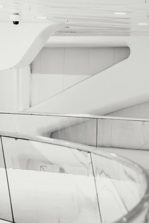 a black and white photo of a spiral staircase, inspired by Zaha Hadid, unsplash contest winner, minimalism, all white, at a mall, glazed, white and silver