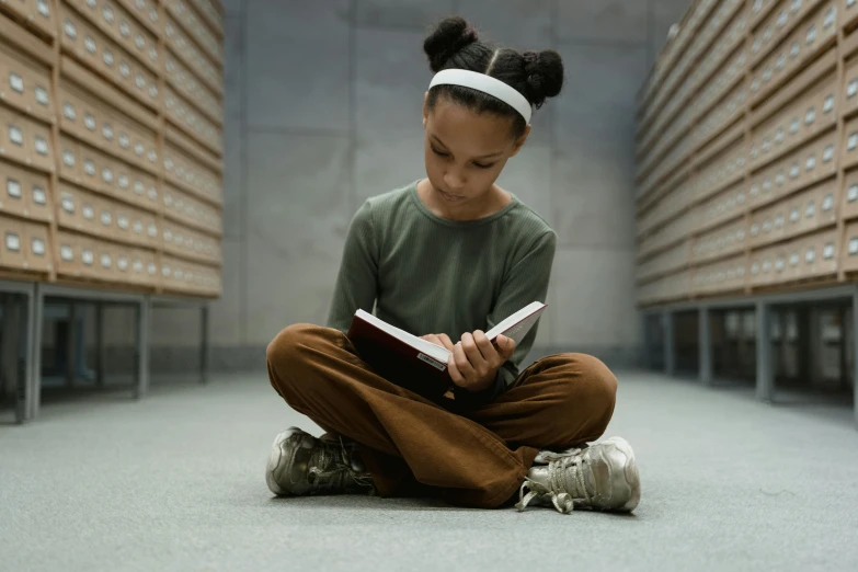 a young girl sitting on the floor reading a book, pexels contest winner, academic art, nerdy black girl super hero, girl with brown hair, girl with plaits, old library
