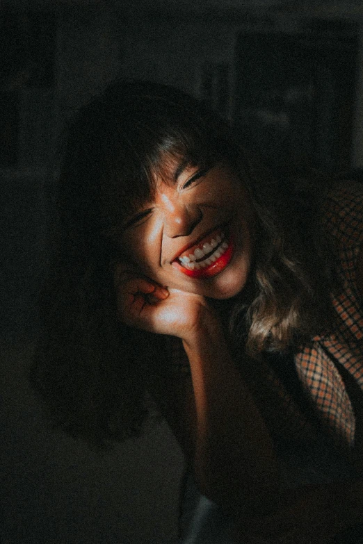 a woman laying on top of a bed next to a window, pexels contest winner, happening, cheeky smile with red lips, in front of a black background, blunt bangs fall on her forehead, mutahar laughing