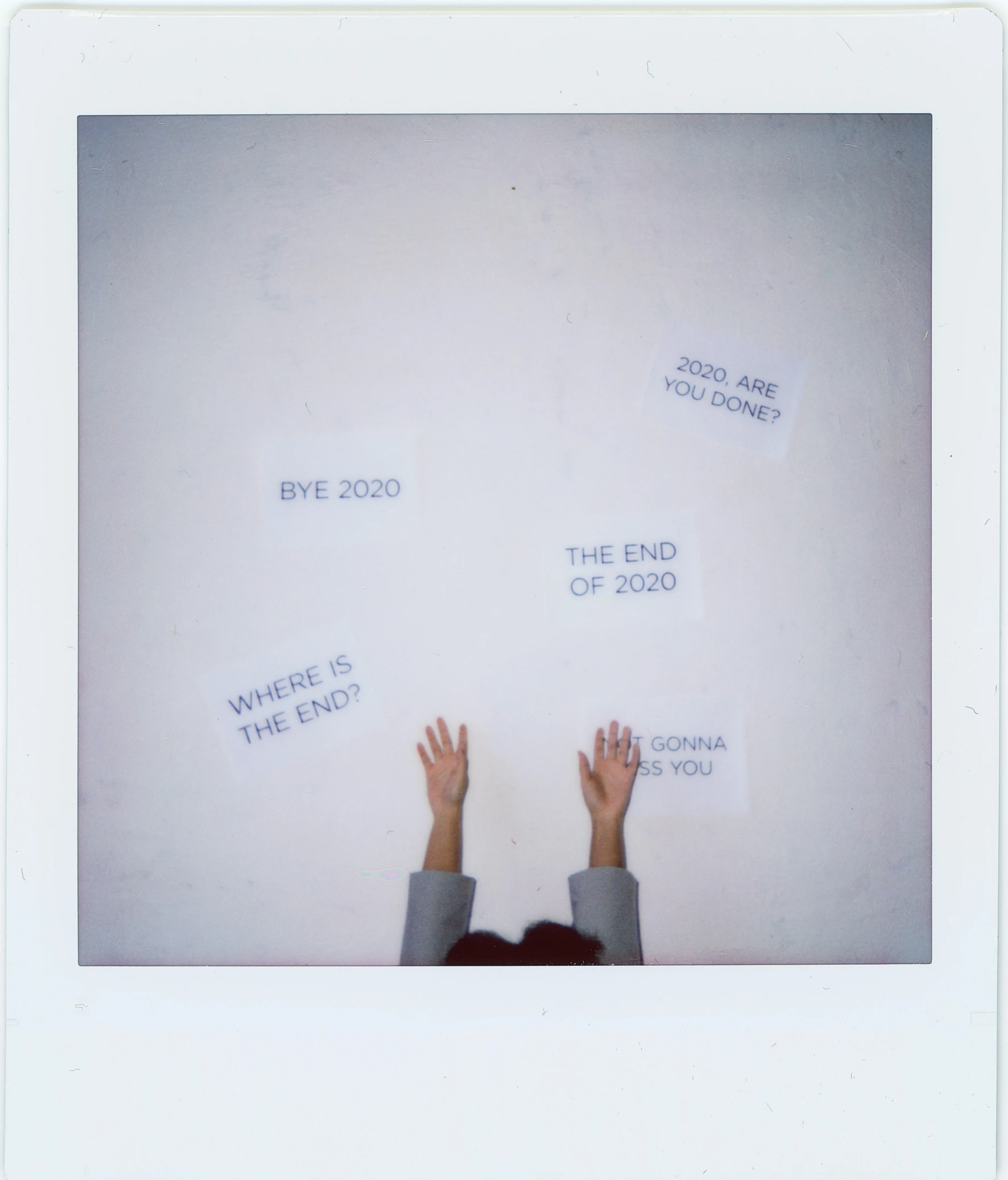 a person holding a sign in front of a wall, a polaroid photo, by Jang Seung-eop, unsplash, temporary art, \'the end, in a white room, hands in the air, 2000s photo