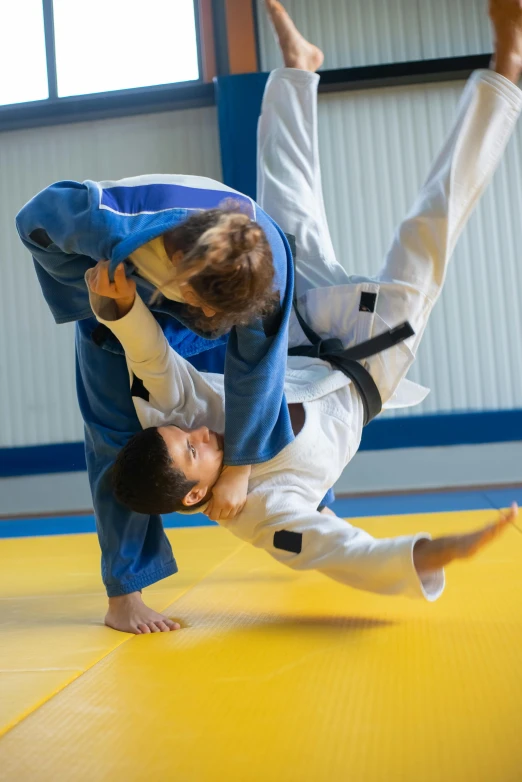 a couple of men standing on top of a yellow mat, pexels contest winner, arabesque, white belt, mid action, wearing blue robe, thumbnail