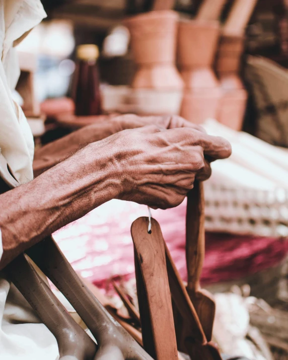 a close up of a person sitting in a chair, by Joseph Henderson, trending on unsplash, inside an arabian market bazaar, holding a wooden staff, two old people, sustainable materials