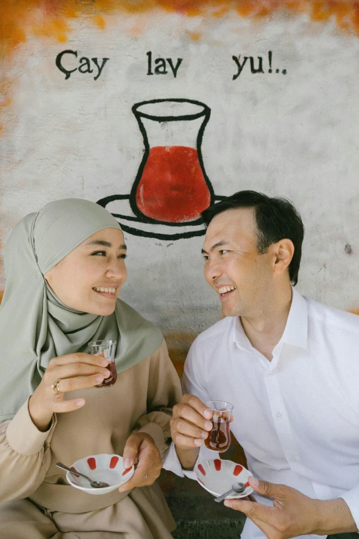 a man and a woman sitting next to each other, by Basuki Abdullah, pexels contest winner, hurufiyya, with a drink, background image, on a table, square