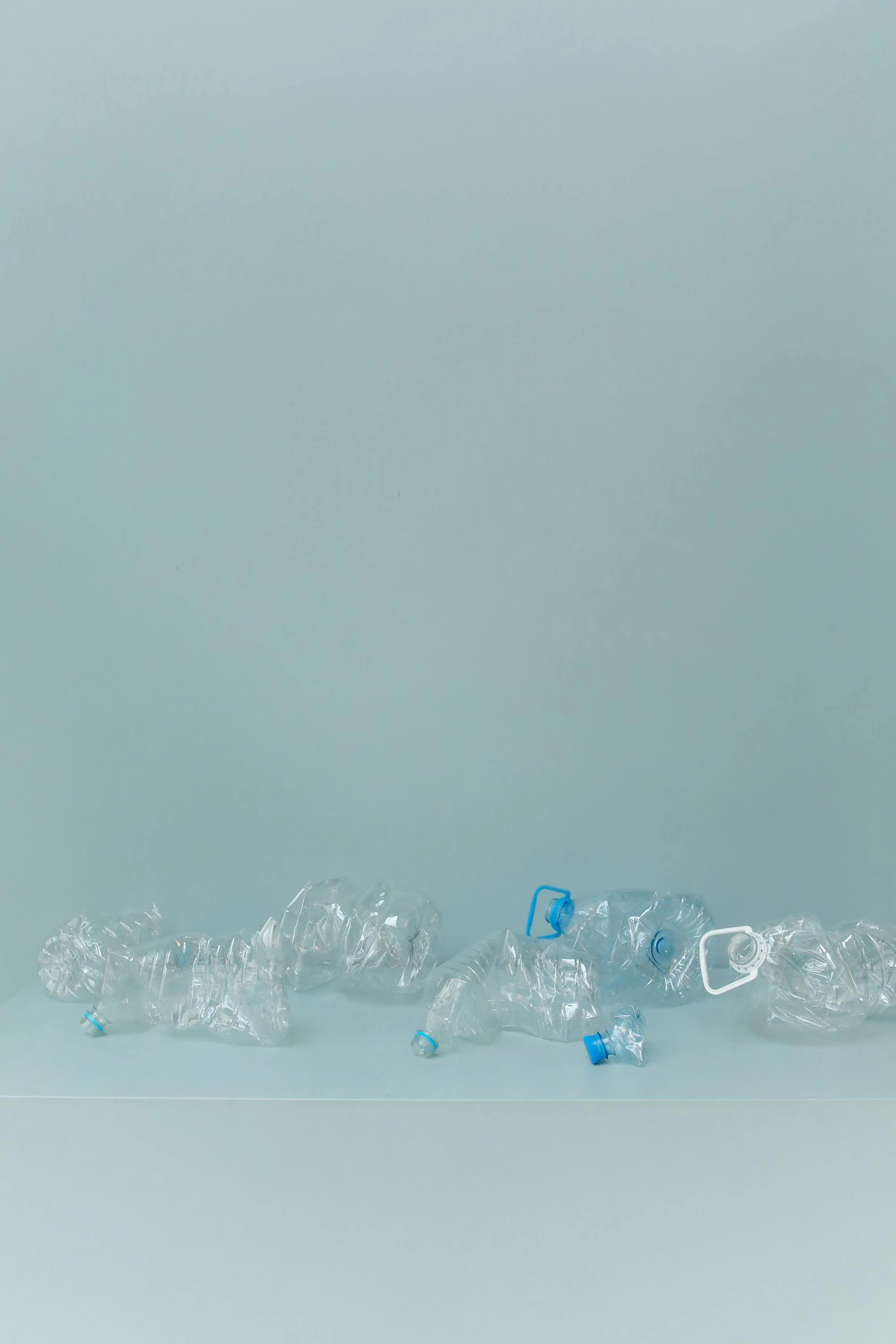 a bottle of water sitting on top of a table, an album cover, by Jessie Algie, unsplash, plasticien, plastic waste, inflateble shapes, lined up horizontally, blue transparent jelly