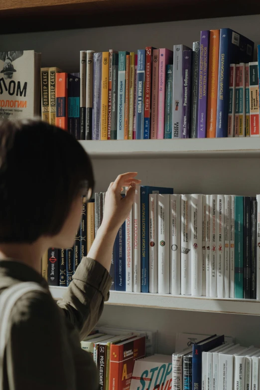 a woman standing in front of a book shelf filled with books, pexels contest winner, japanese collection product, programming, facing sideways, gif