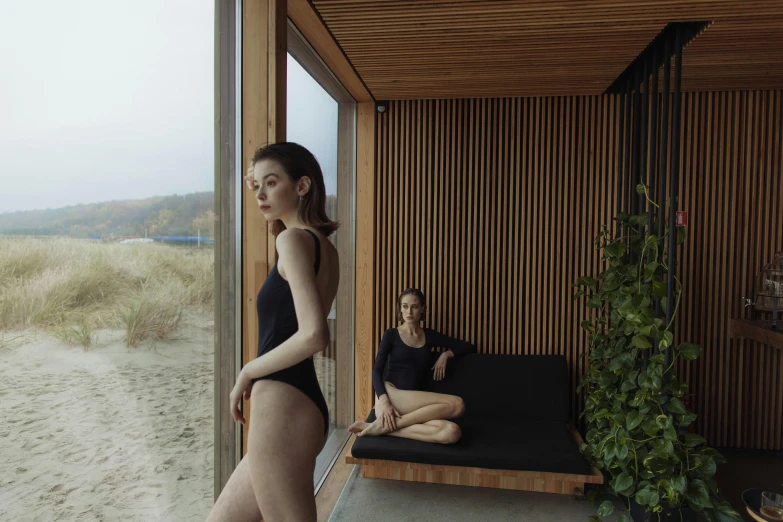 two women sitting on a couch in a room, inspired by Vanessa Beecroft, unsplash contest winner, standing near the beach, sauna, black swimsuit, nature outside