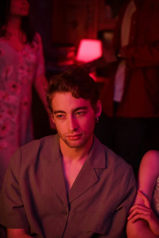 a man and a woman sitting next to each other, an album cover, inspired by Nan Goldin, trending on pexels, robert sheehan, glowing pink face, chillin at the club together, 15081959 21121991 01012000 4k