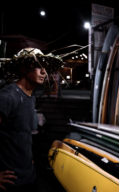 a man standing next to a bunch of surfboards, pexels contest winner, afrofuturism, scrap metal headdress, on black background, covered with wires, inside of a tokyo garage