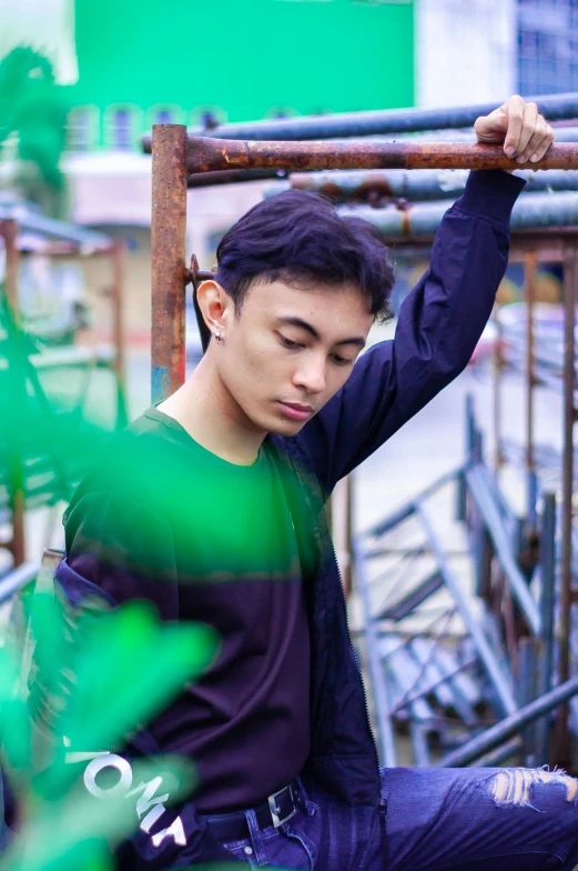 a man sitting on top of a metal pole, a picture, inspired by Adam Dario Keel, pexels contest winner, sumatraism, halfbody headshot, greens), androgynous person, he is about 20 years old | short