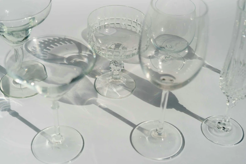 a group of wine glasses sitting on top of a table, by Nina Hamnett, vintage shapes, cocktail in an engraved glass, sport glasses, white