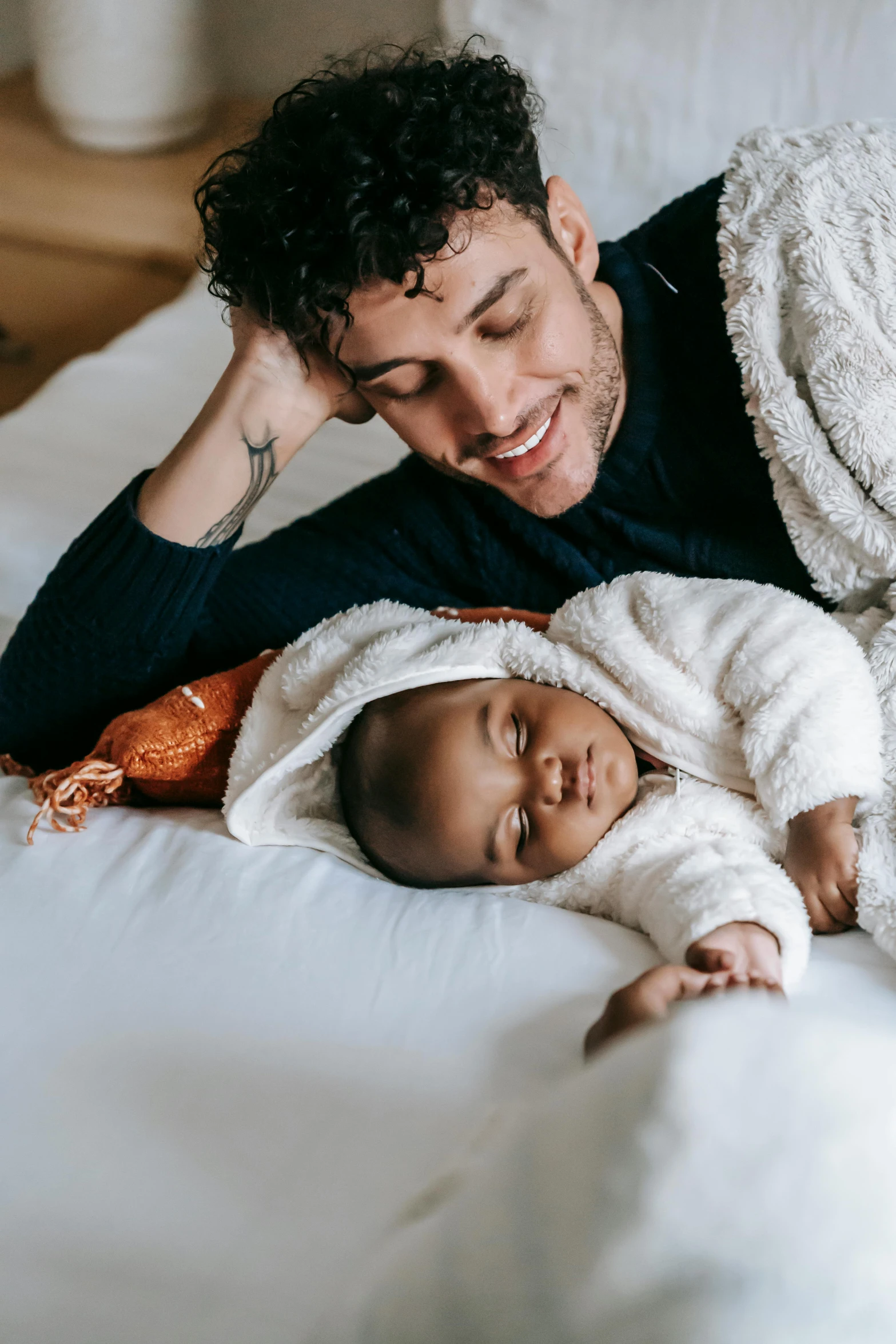 a man laying on top of a bed next to a baby, pexels contest winner, renaissance, mixed race, supportive, lightly dressed, profile image