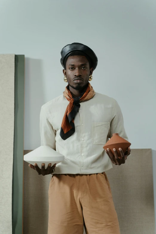 a man in a white shirt and brown pants, inspired by Theo Constanté, afrofuturism, contemporary ceramics, off - white collection, promotional image, holding a stuff