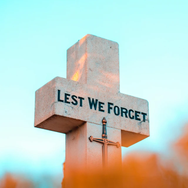 a cross with the words lest we forget on it, an album cover, unsplash, avatar image, monument, no watermark, 2025