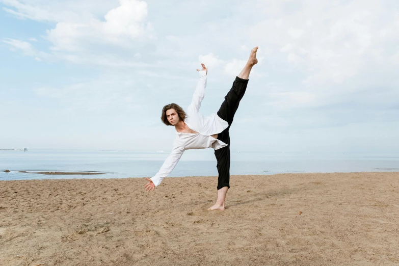 a woman doing a handstand on the beach, an album cover, unsplash, arabesque, actor, joe keery, he is dancing, white