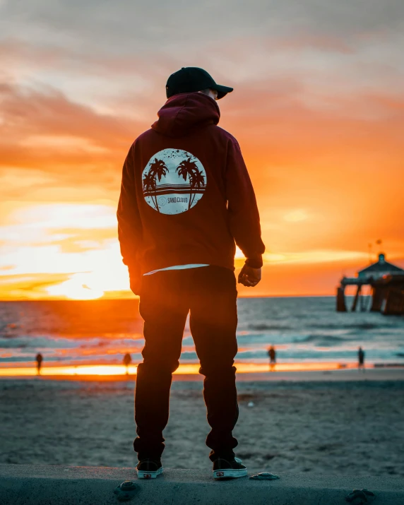 a man standing on top of a beach next to the ocean, streetwear, profile image, red sunset, street clothing