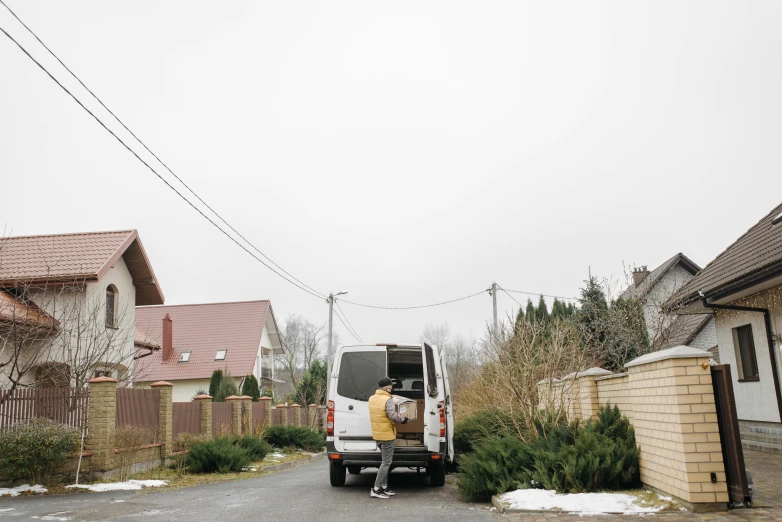 a man that is standing in the back of a truck, by Attila Meszlenyi, pexels contest winner, in a suburban backyard, van, driveway, anna podedworna