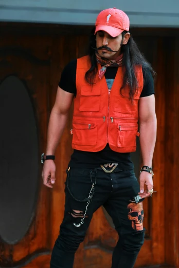 a man standing on a skateboard in front of a building, inspired by Yasutomo Oka, sots art, black leather vest is open, long hair and red shirt, with mustache, model is wearing techtical vest