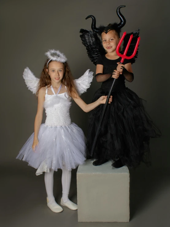 two little girls dressed up in halloween costumes, by Lynn Pauley, pexels contest winner, international gothic, tall female angel, on a gray background, soft devil queen madison beer, ( ( theatrical ) )