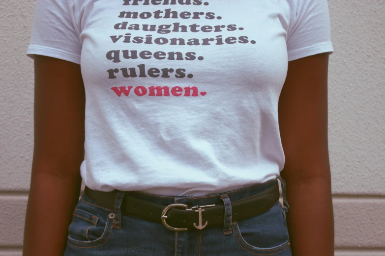 a woman wearing a t - shirt that says friends, daughters, daughters, queens, rulers, rulers, women, by Hannah Tompkins, trending on pexels, feminist art, waist - shot, nuri iyem, delicate details, ( ( ( wearing jeans ) ) )