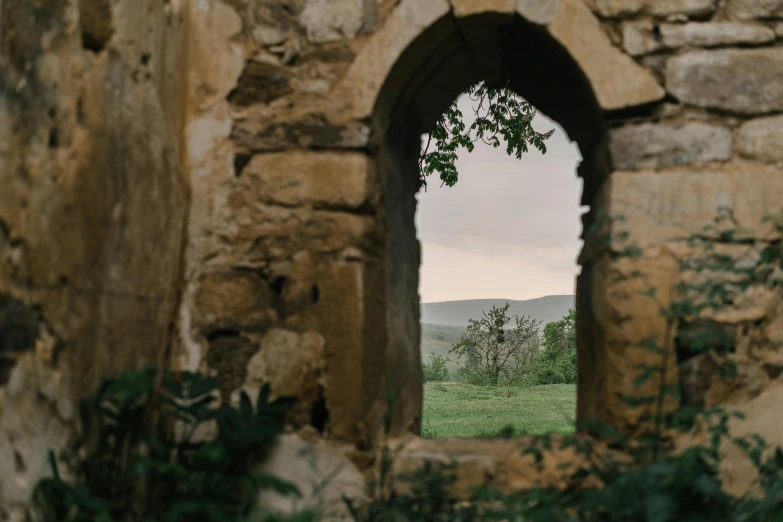 a window in a stone wall with a view of a field, by Emma Andijewska, unsplash contest winner, renaissance, gothic arch frame, lourmarin, standing in ruins, archways made of lush greenery