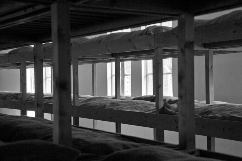 a black and white photo of a row of bunk beds, by Jaakko Mattila, flickr, looking outside, whitewashed housed, cell bars, white bed