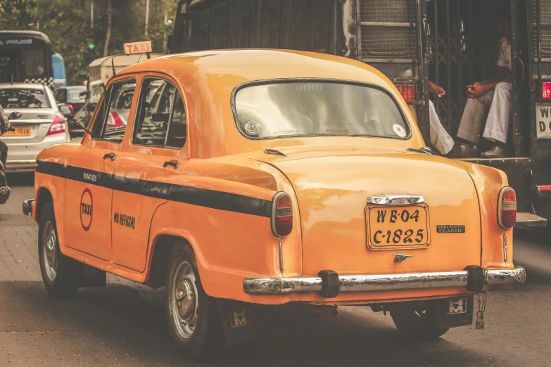 an orange taxi cab driving down a busy street, pexels contest winner, old dhaka, yellow and black trim, square, vintage inspired