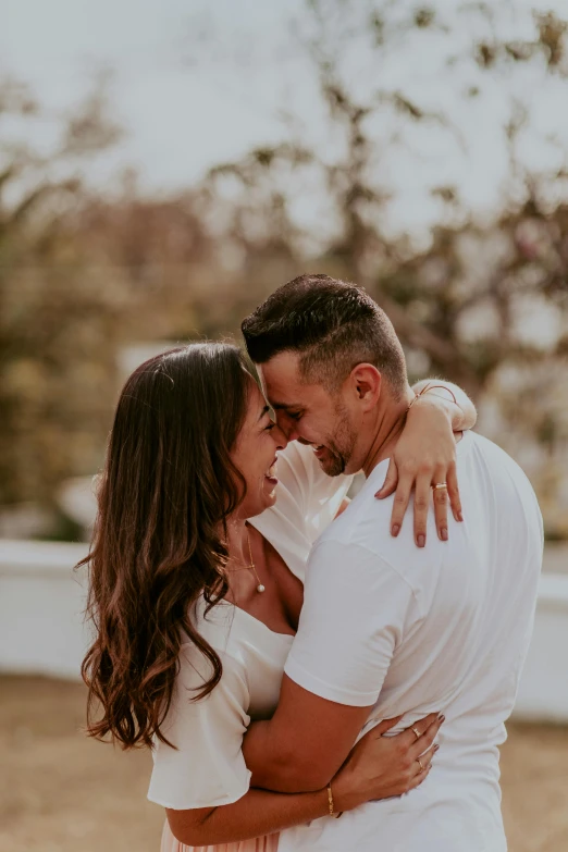 a man and woman hugging each other in a field, pexels contest winner, dressed in a white t shirt, profile image, brunette, hearts