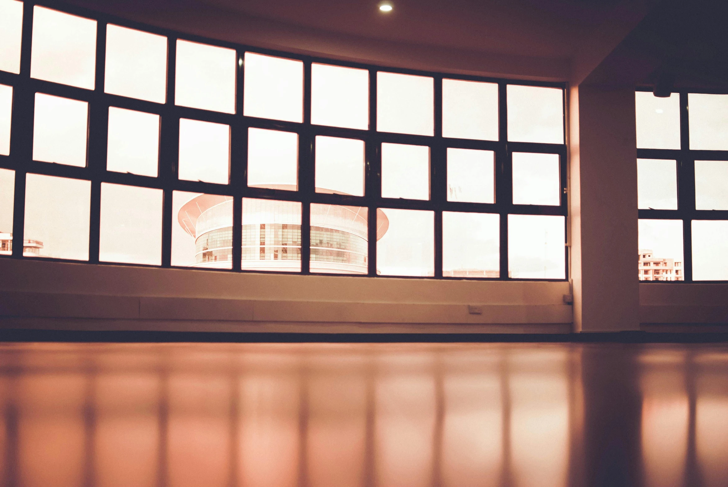 a cat sitting on the floor in front of a window, a cartoon, unsplash, light and space, james turrell building, photo of a classroom, large round window, faded glow