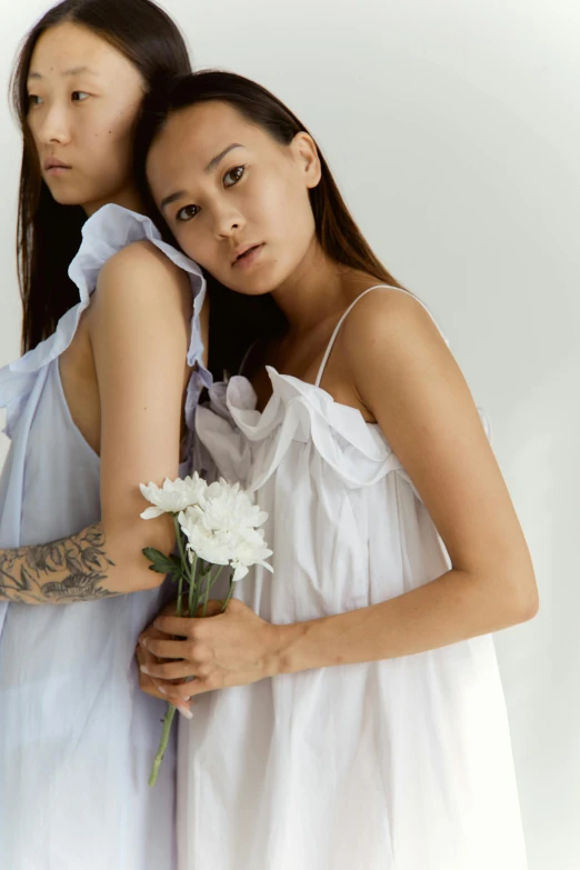 a couple of women standing next to each other, inspired by Cui Bai, trending on pexels, renaissance, white sundress, non binary model, soft flowers, asian descent