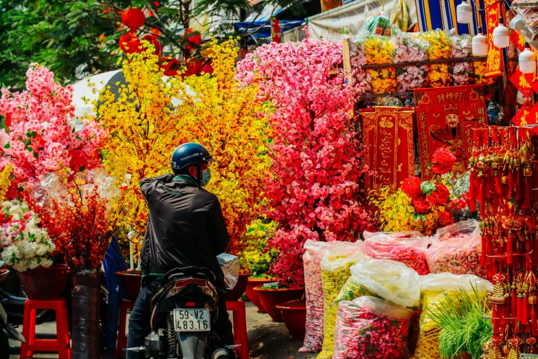 a man riding a motorcycle through a flower market, brightly coloured, red and yellow color scheme, flower decorations, 🌸 🌼 💮