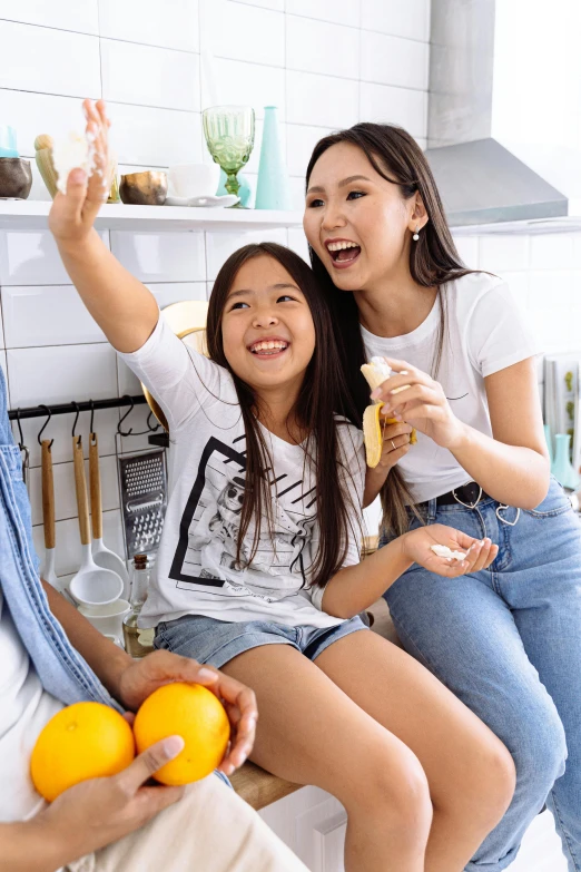 a family taking a selfie in the kitchen, a picture, shutterstock contest winner, asian girl with long hair, banana, holding a tangerine, 15081959 21121991 01012000 4k