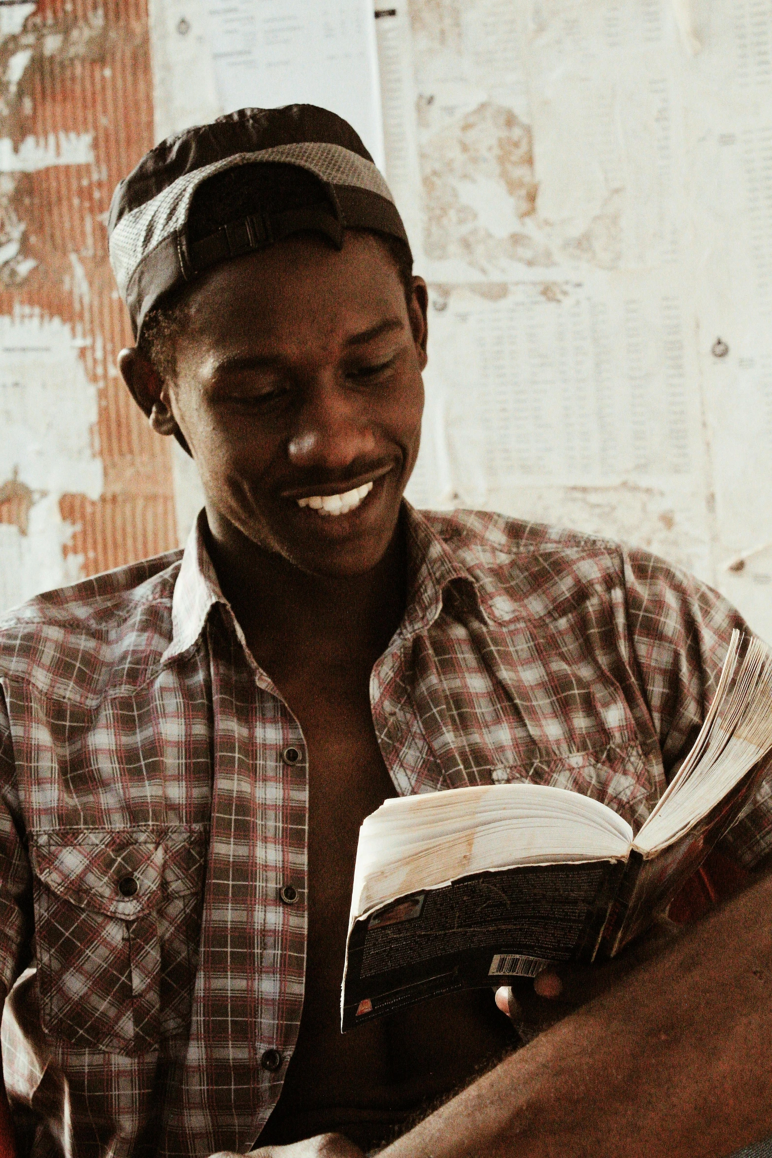 a man sitting on a couch reading a book, by Ingrida Kadaka, brown skin man with a giant grin, an open book, young almighty god, profile image