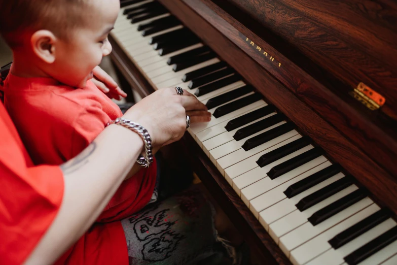 a woman playing a piano with a child, an album cover, pexels, lachlan bailey, half image, 1 2 9 7