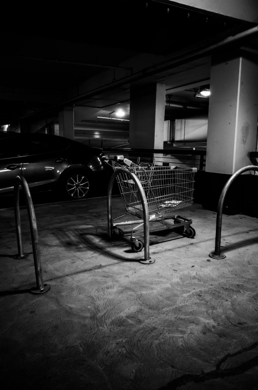 a black and white photo of a shopping cart in a parking garage, ((still life)), dark vibes, inside a supermarket, so come on