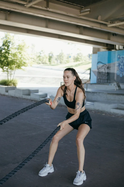 a woman holding a rope in a parking lot, working out, lachlan bailey, profile image, gnarled