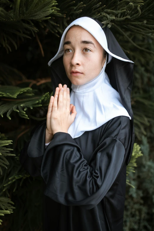 a woman dressed as a nun standing in front of a tree, a portrait, inspired by Louis Le Nain, unsplash, teenage girl, blessing palms, actors, in black uniform