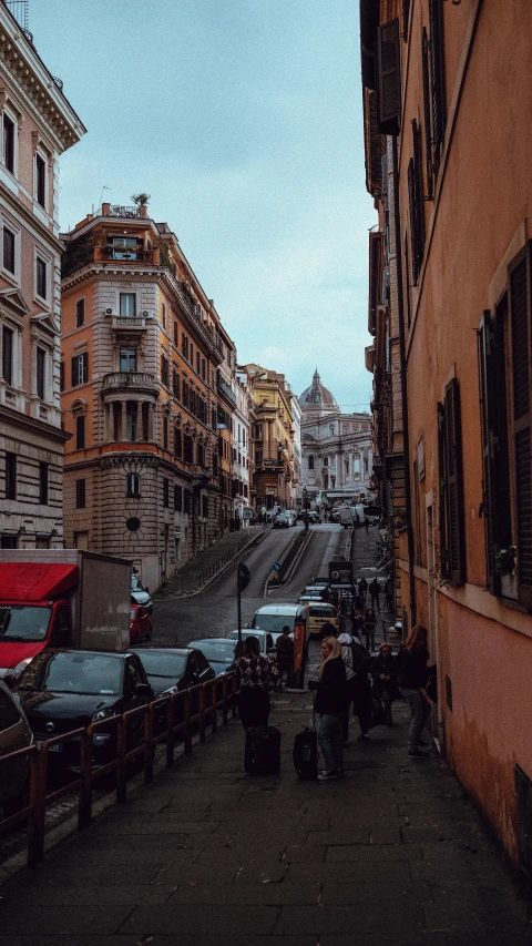 a group of people walking down a street next to tall buildings, by Alessandro Allori, pexels contest winner, renaissance, terraced, roman, built on a steep hill, cars parked underneath