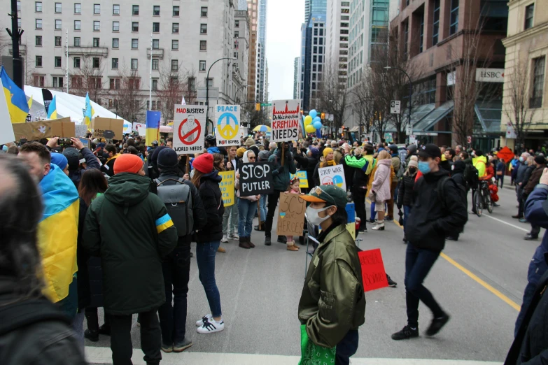 a large group of people walking down a street, vancouver, ukrainian flag on the left side, placards, avatar image