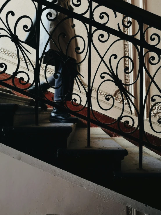 a person walking down a set of stairs, inspired by Louis Stettner, pexels contest winner, art nouveau, red and black details, baroque objects, ( ( theatrical ) ), wrought iron