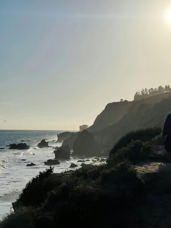 a person sitting on the edge of a cliff overlooking the ocean, pch, profile image