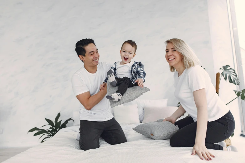 a man and woman sitting on a bed with a baby, inspired by The Family Circus, pexels contest winner, minimalism, smiling laughing, damien tran, te pae, smiling at camera