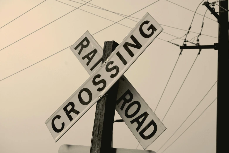 a black and white photo of a railroad crossing sign, an album cover, unsplash, raging, cross-hatchings, 2000s photo, racing