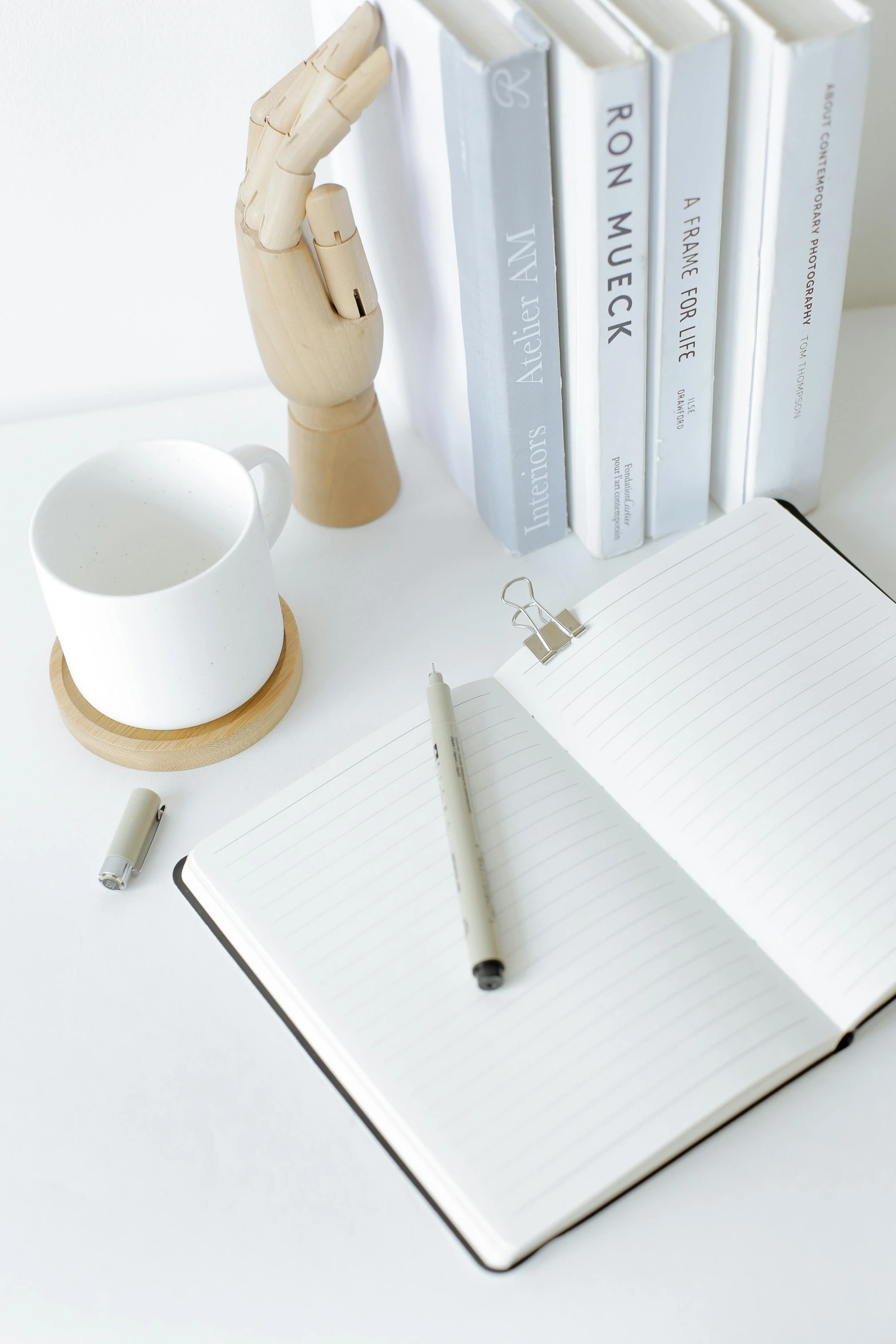 a stack of books sitting on top of a table next to a cup of coffee, by Nicolette Macnamara, unsplash, pen on white paper, japanese collection product, holding notebook, silver，ivory