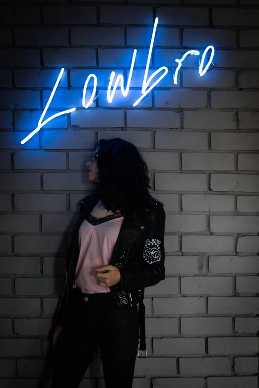 a woman standing in front of a brick wall, an album cover, inspired by Nan Goldin, unsplash contest winner, lowbrow, neon!! light, libra, l · lawliet, jacket