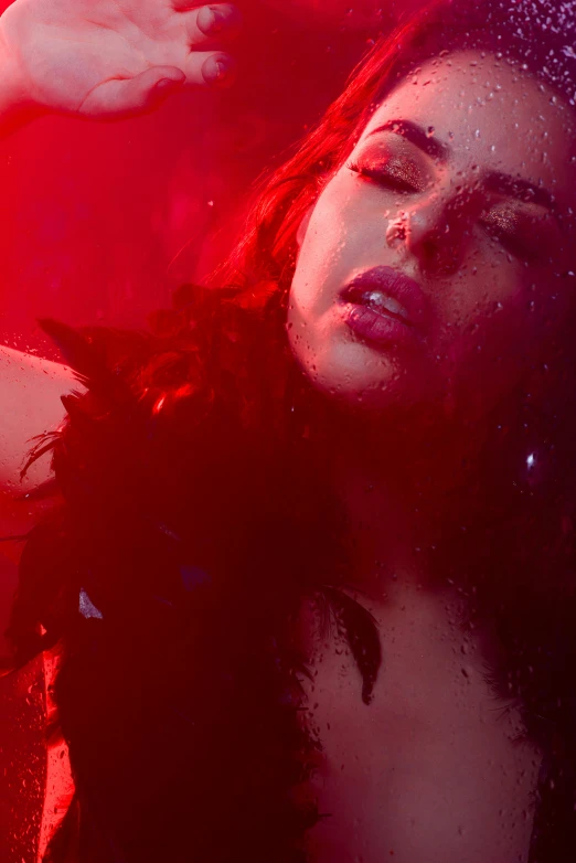 a woman standing in front of a red light, an album cover, inspired by Elsa Bleda, trending on pexels, renaissance, honey birdette, feathers ) wet, still from a music video, showstudio