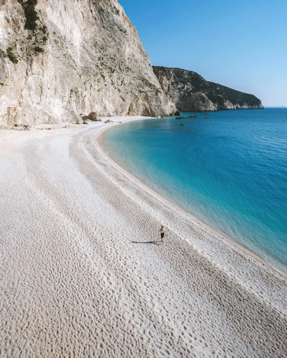 a person walking on a beach next to the ocean, greek nose, insanely beautiful, laying on beach, lgbtq