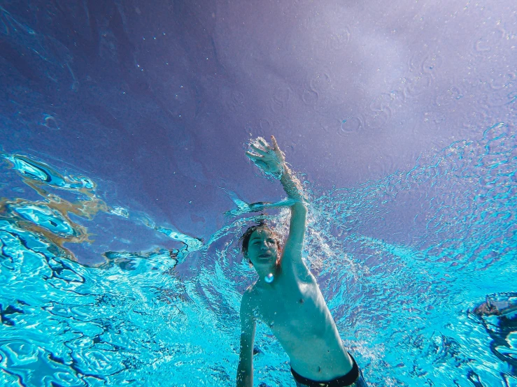 a man swimming under water in a pool, unsplash, fan favorite, happy kid, ultrawide shots, waving